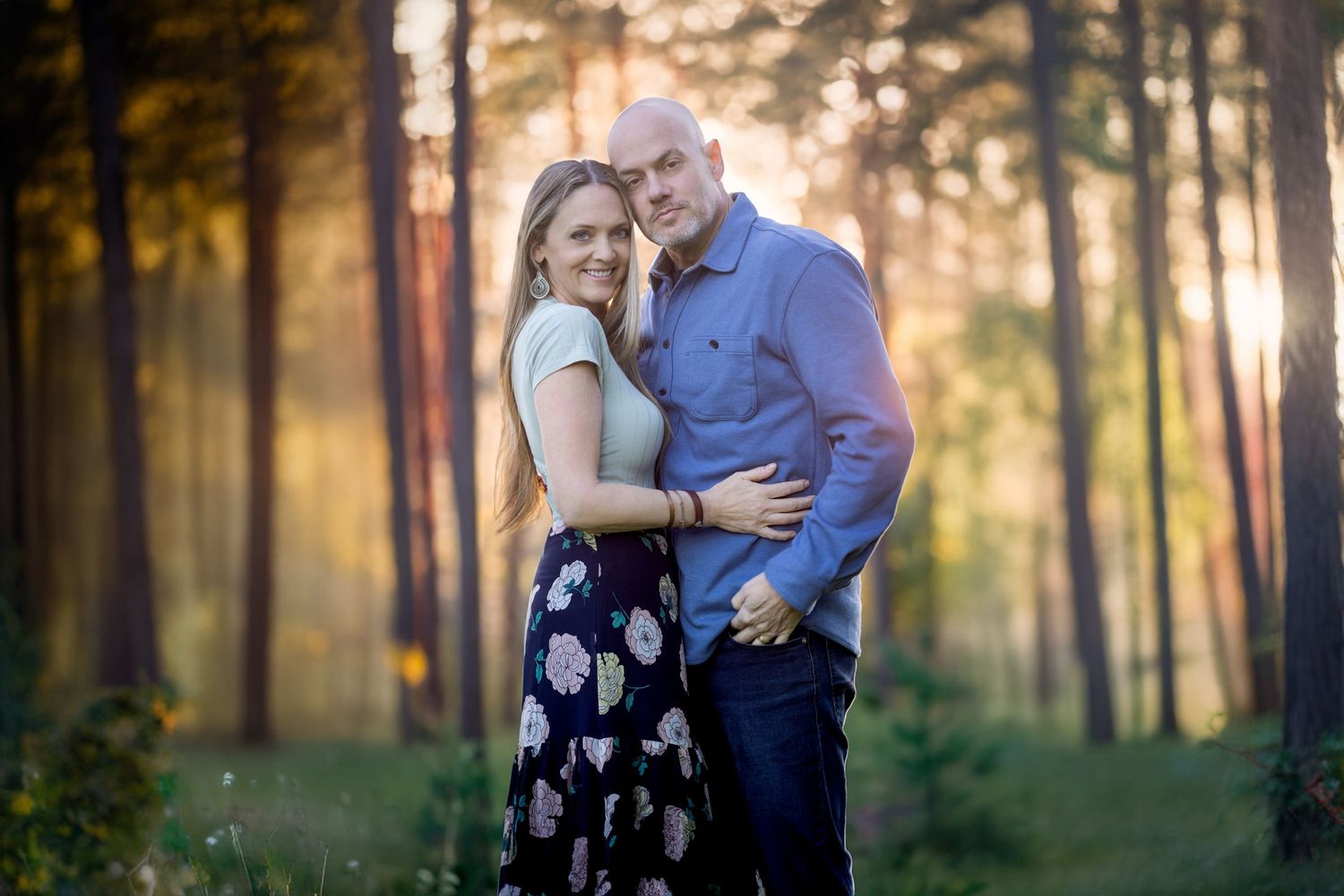 Romantic engagement photo shoot in a sunlit forest setting during golden hour.