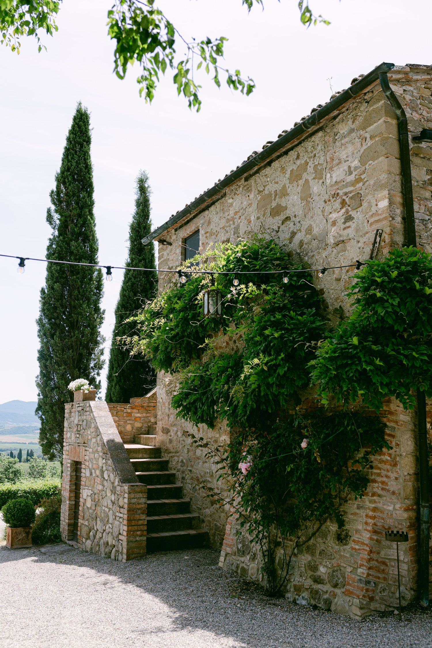 A picturesque Italian stone farmhouse with climbing vines and rustic stone steps at Borgo di Castelvecchio.