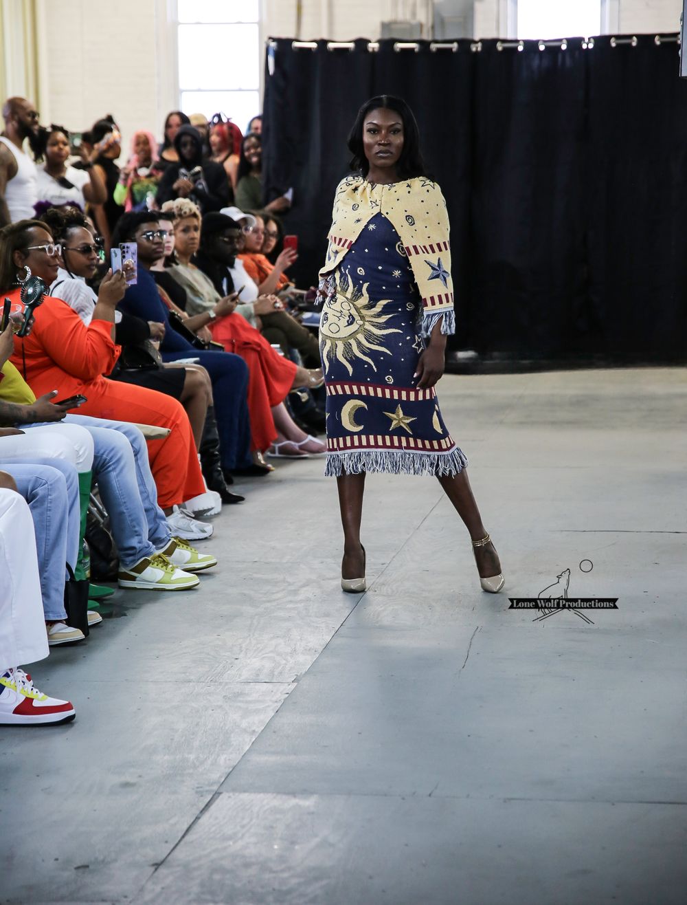 Runway show features dramatic celestial-patterned dress with sun and moon designs.