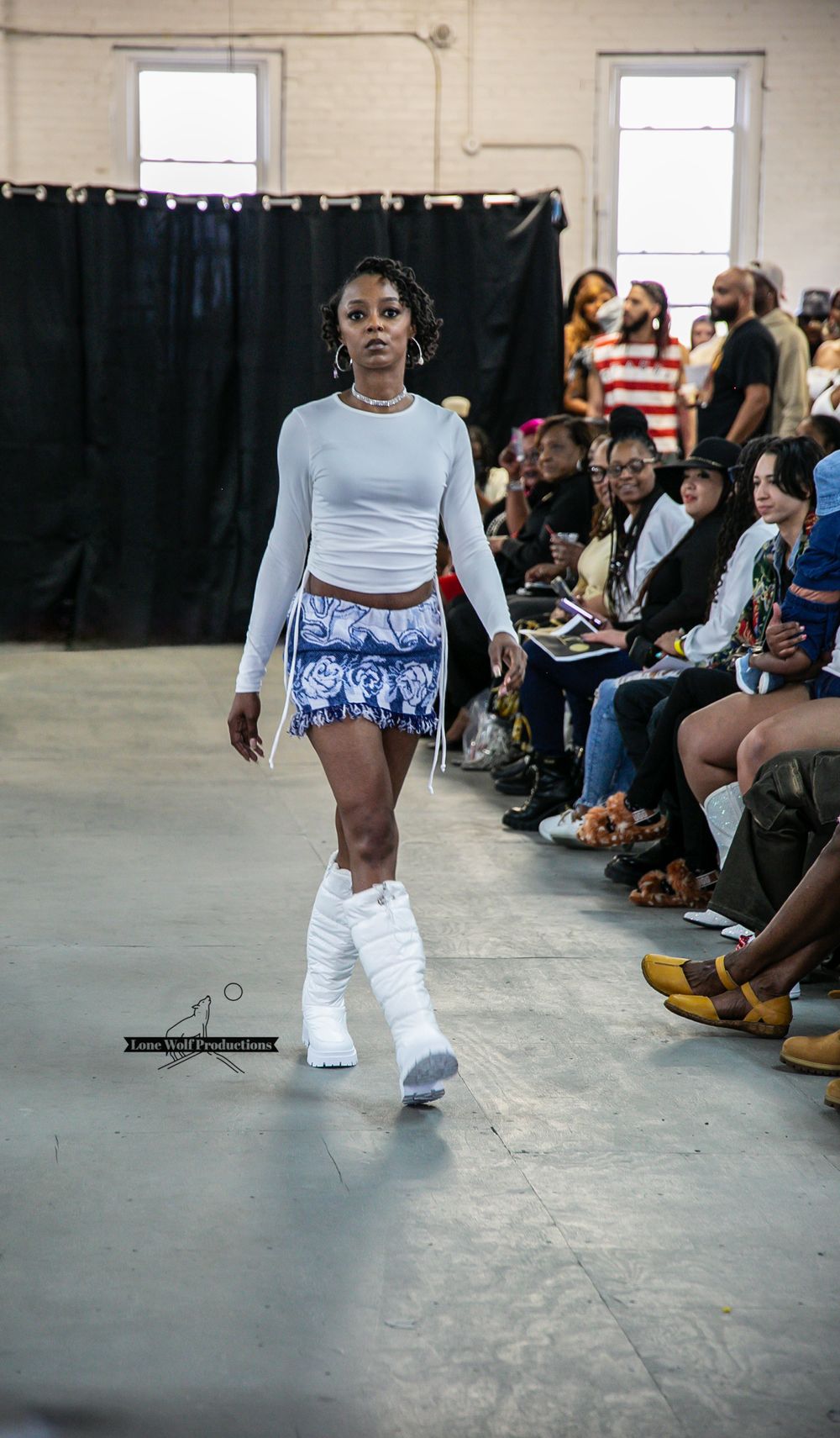 Model struts in light blue crop top with patterned shorts and white platform boots.