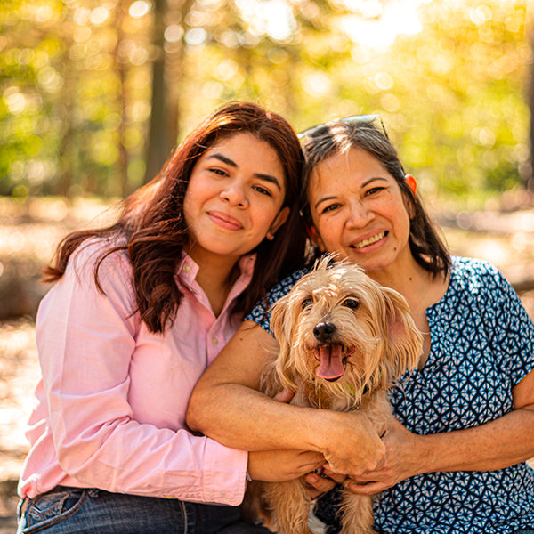 Small terrier dog being held during autumn outdoor photoshoot.