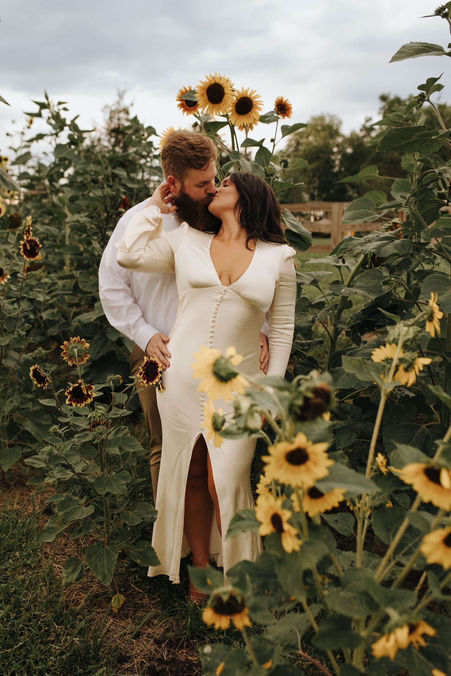 Intimate kiss shared between newly engaged couple amongst towering sunflowers at Retreat 21 wedding venue in Marysville, Ohio.