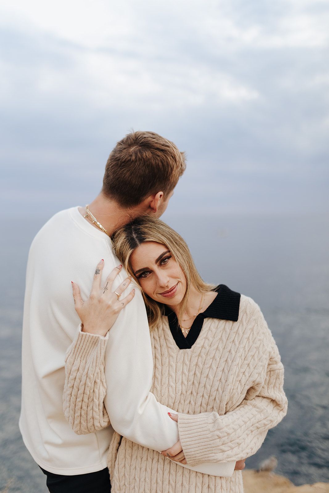 Couple embracing on cliff overlooking the ocean in Ocean Beach, San Diego.