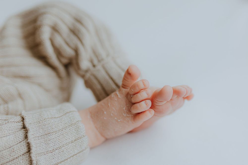 Close-up of tiny newborn baby feet wrapped in soft knit fabric.