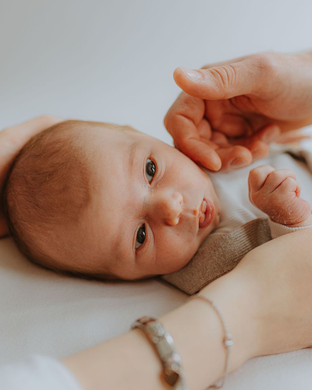Close-up profile of newborn baby lying on soft beige fabric.