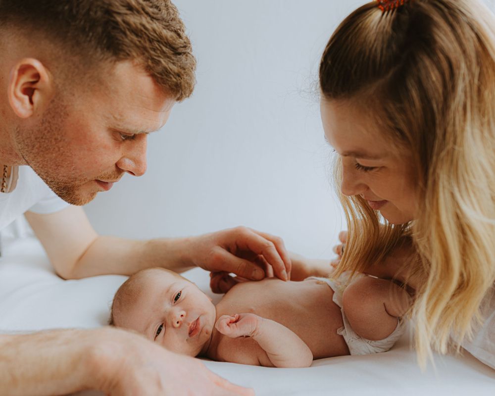 Sweet family bonding moment with newborn baby in natural light setting.