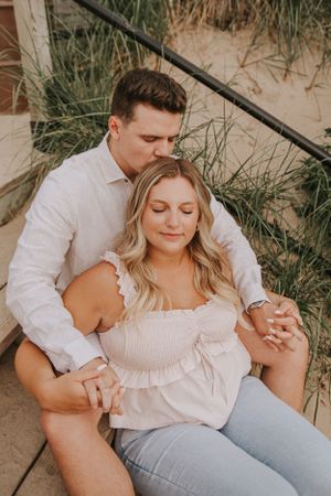 A tender moment between a couple sitting on wooden steps at the beach.