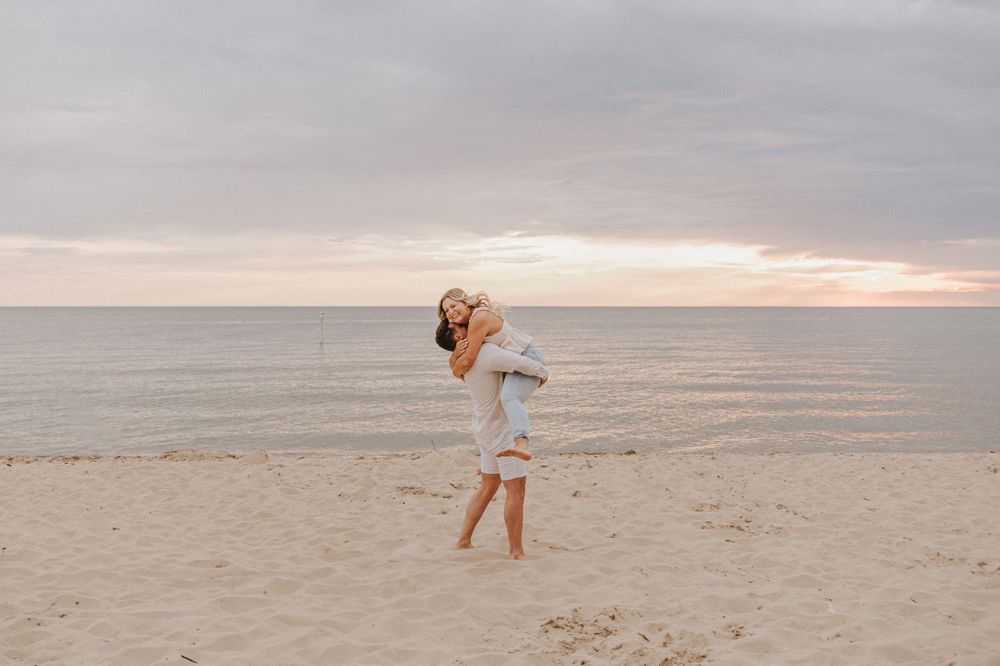 A joyful embrace captured on a beach at sunset with ocean in background.