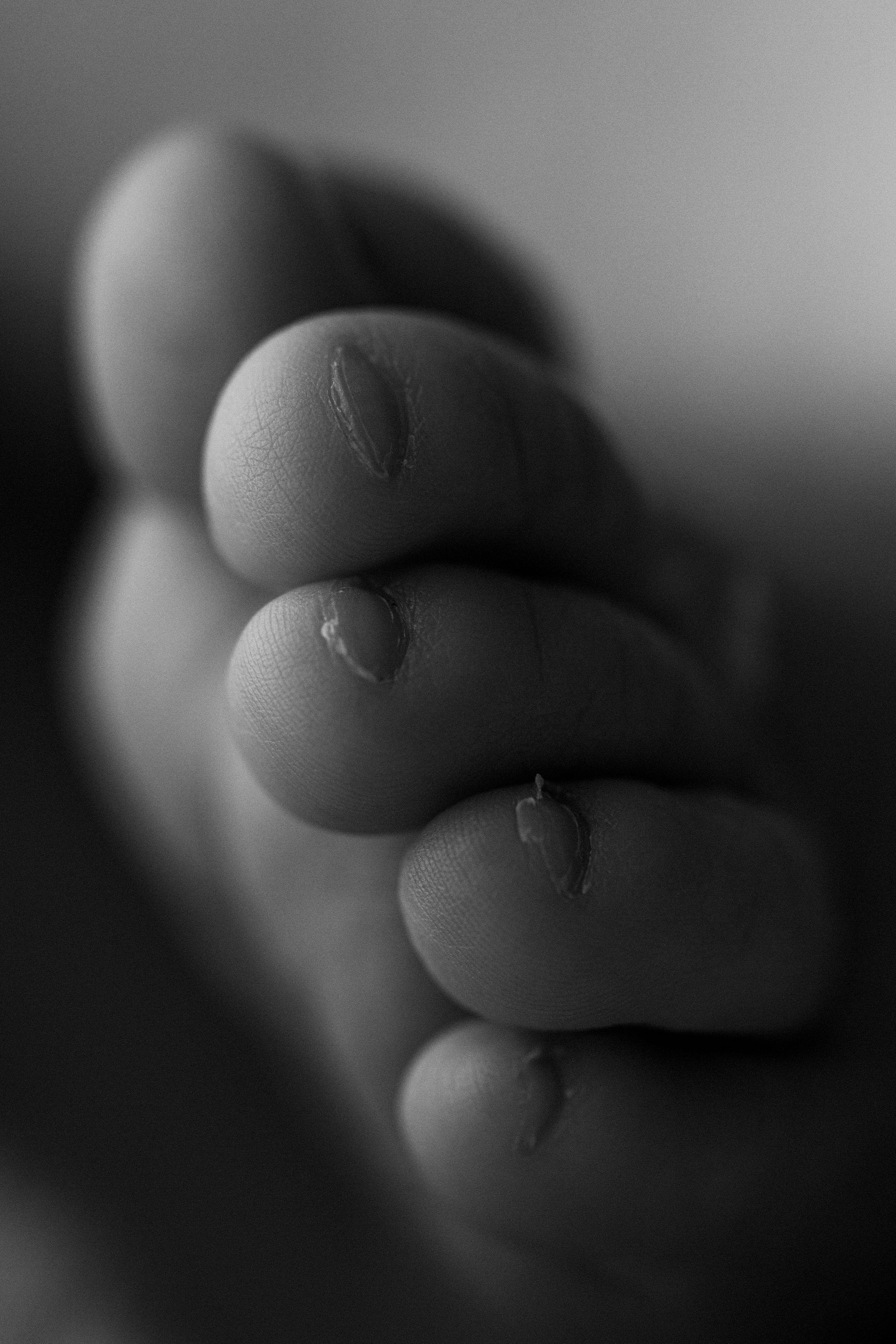 Close-up black and white macro photograph of fingertips showing fine details and texture.