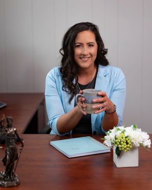 Professional office portrait with someone holding a coffee cup at a desk with flowers.