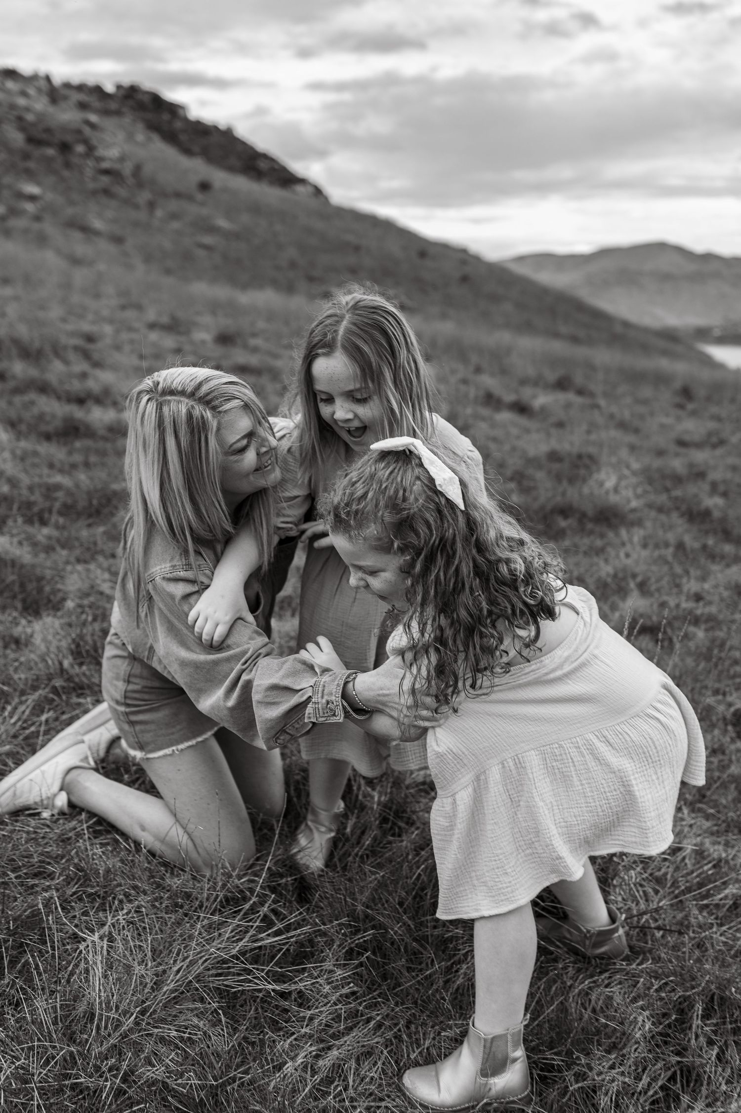 A joyful moment captured in black and white on a hillside with mountains in the distance.