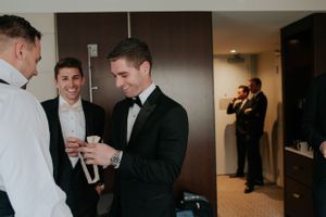 Groomsmen in formal attire laughing and getting ready together before the ceremony.