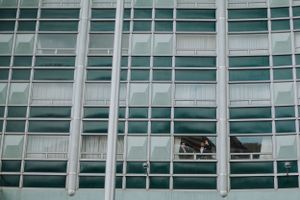 Modern high-rise building with glass windows and a wedding photoshoot visible through one pane.