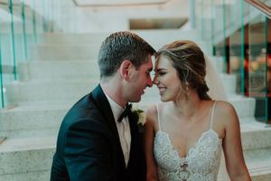 A romantic wedding moment captured in a teal-tinted setting with the couple sharing an intimate pose on stone steps.