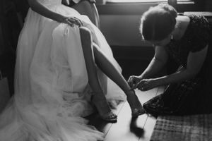 Black and white image of wedding dress preparation with final details being attended to.