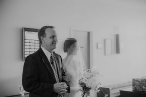 Black and white candid moment before wedding ceremony with bouquet.