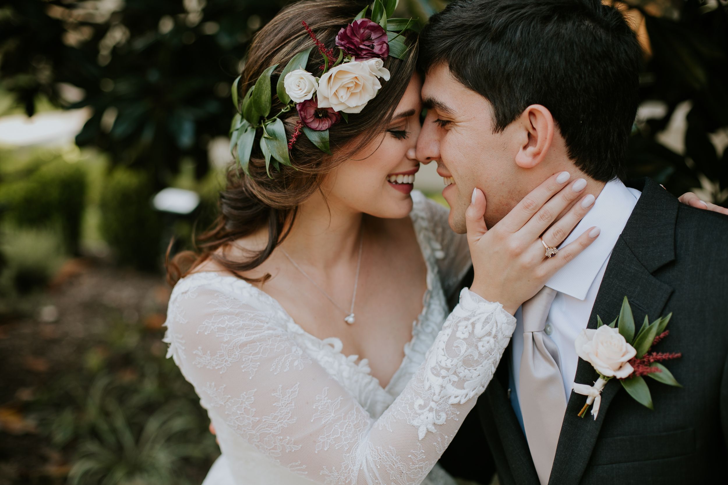 Close up of a romantic wedding moment with bride wearing floral crown and lace sleeves.