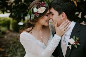 Close up of a romantic wedding moment with bride wearing floral crown and lace sleeves.