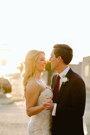 Newlyweds share an intimate moment during golden hour sunset in their wedding attire.