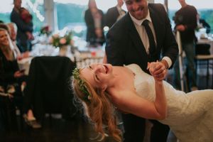 A couple shares a candid moment of laughter and joy while dancing at their wedding reception.
