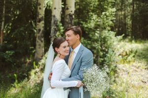 Intimate forest wedding portrait with couple embracing among aspen trees.