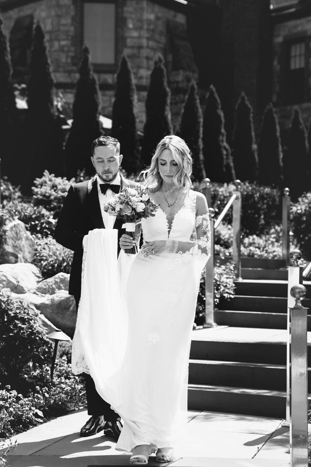 Black and white wedding photos showing a couple posing with white fabric in a garden setting.