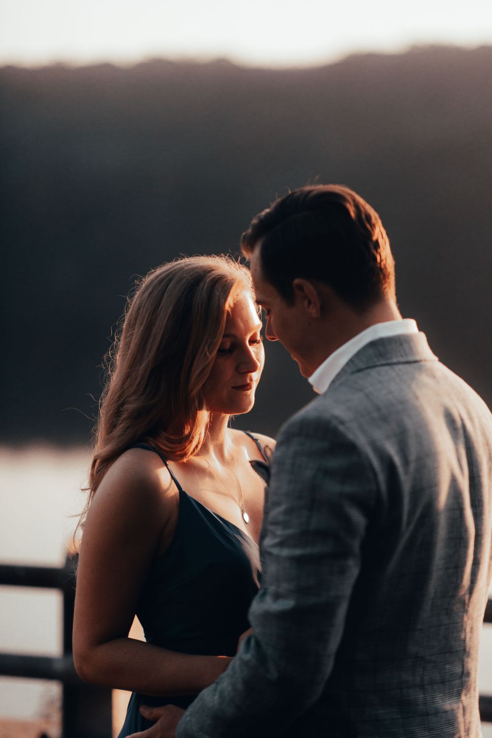 Silhouetted couple shares intimate moments at sunset by the water.