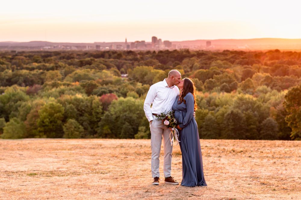 Romantic couple poses against sunset backdrop in scenic outdoor landscape.