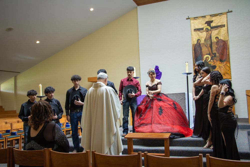 A quinceañera ceremony in a church with guests and a girl in a red ball gown near the altar.