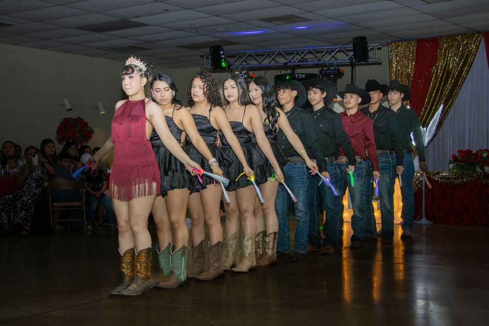 A quinceañera dance court performs a choreographed routine in western attire at the reception hall.