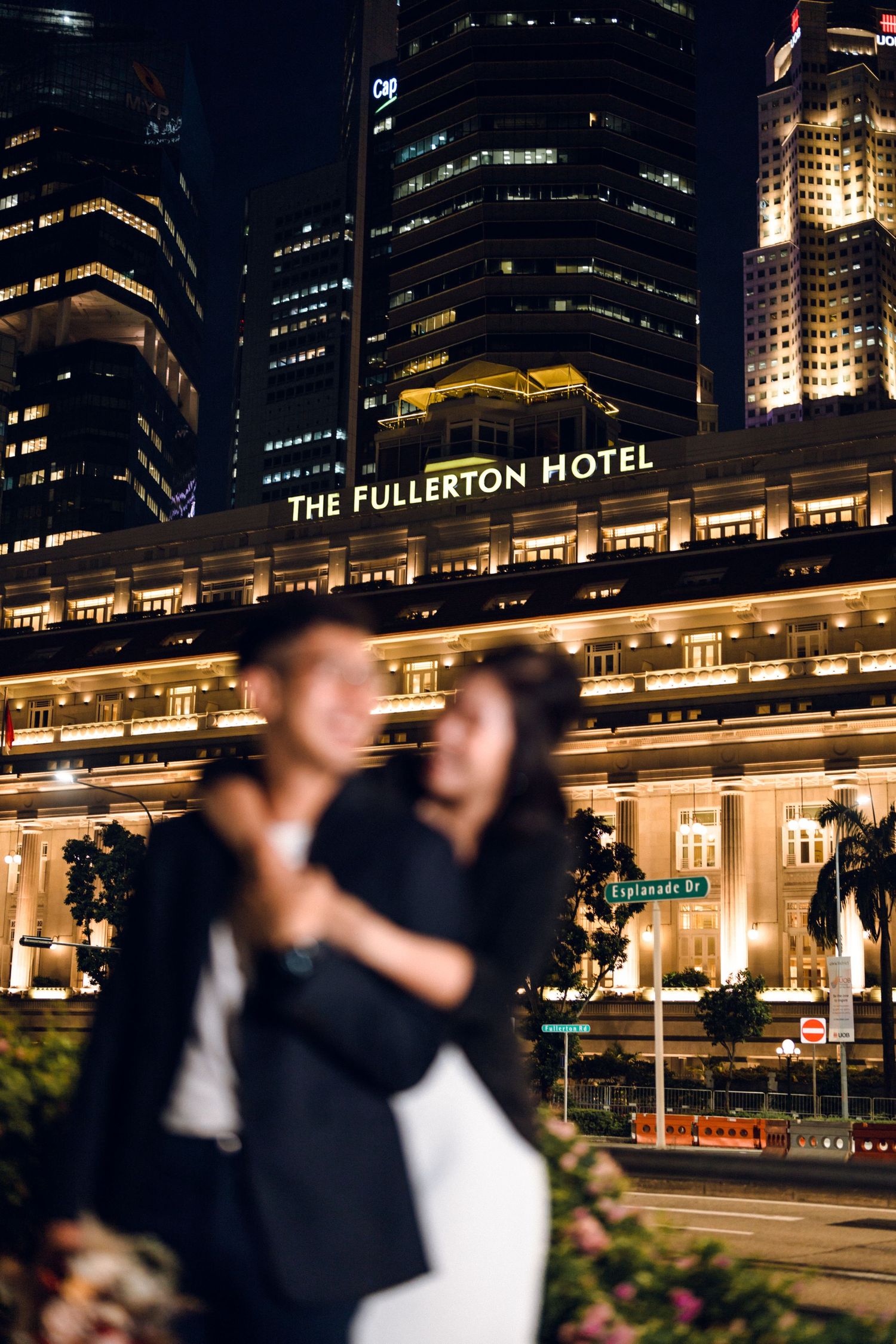Elegant nighttime portrait in front of the historic Fullerton Hotel with glowing city lights.