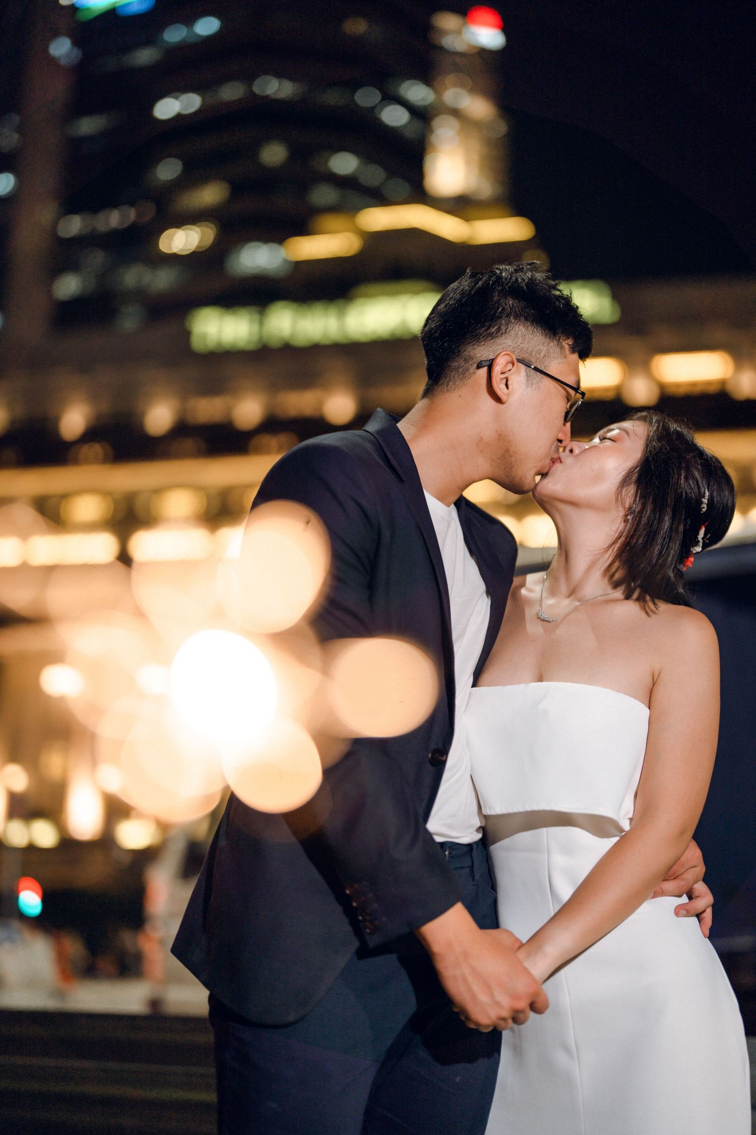 Intimate moment captured between couple during nighttime photoshoot in the city.