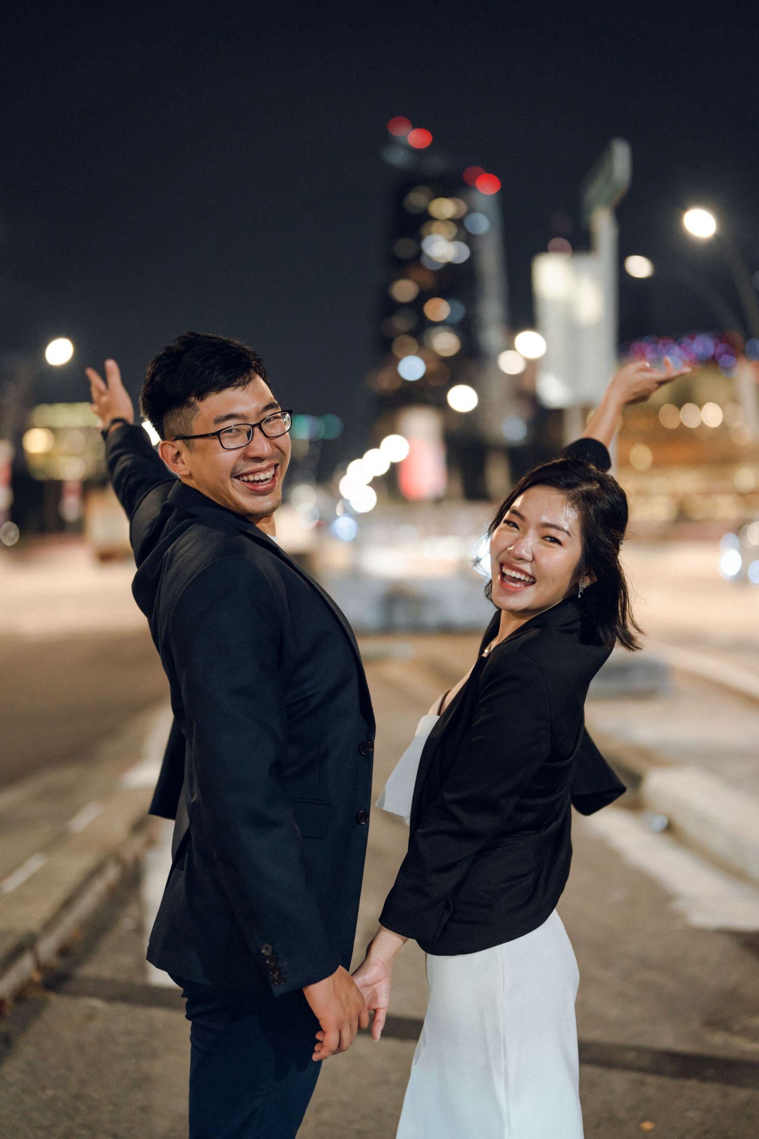 Joyful couple sharing laughs during nighttime photoshoot in urban setting.