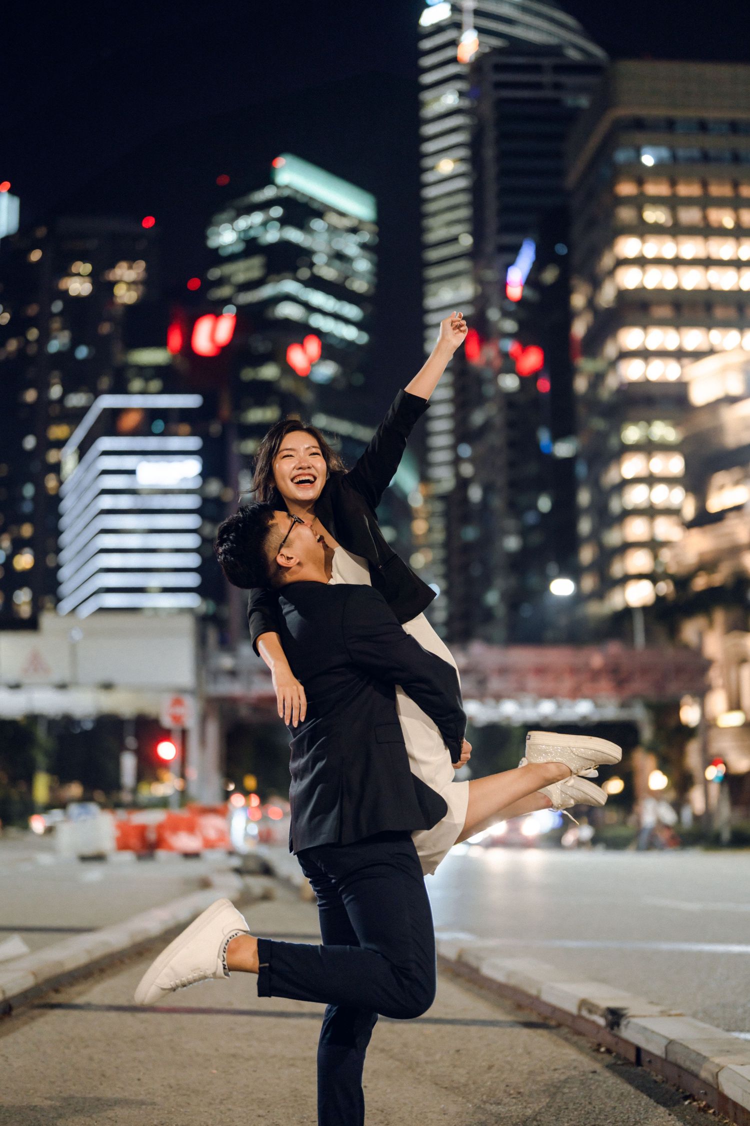 Joyful dance poses against a nighttime cityscape with illuminated buildings in the background.