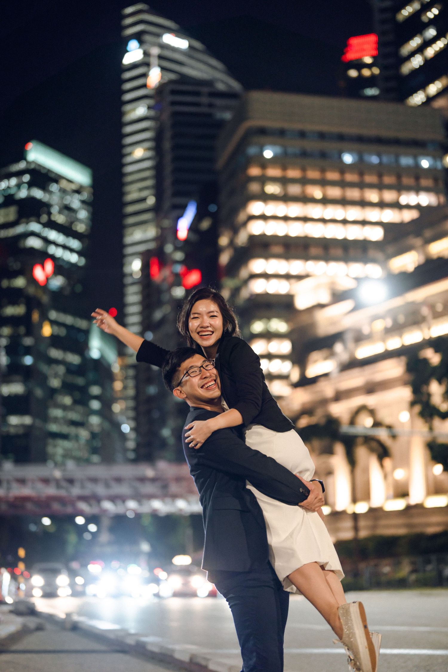 Playful dance movements captured at night with urban skyscrapers creating a dramatic backdrop.