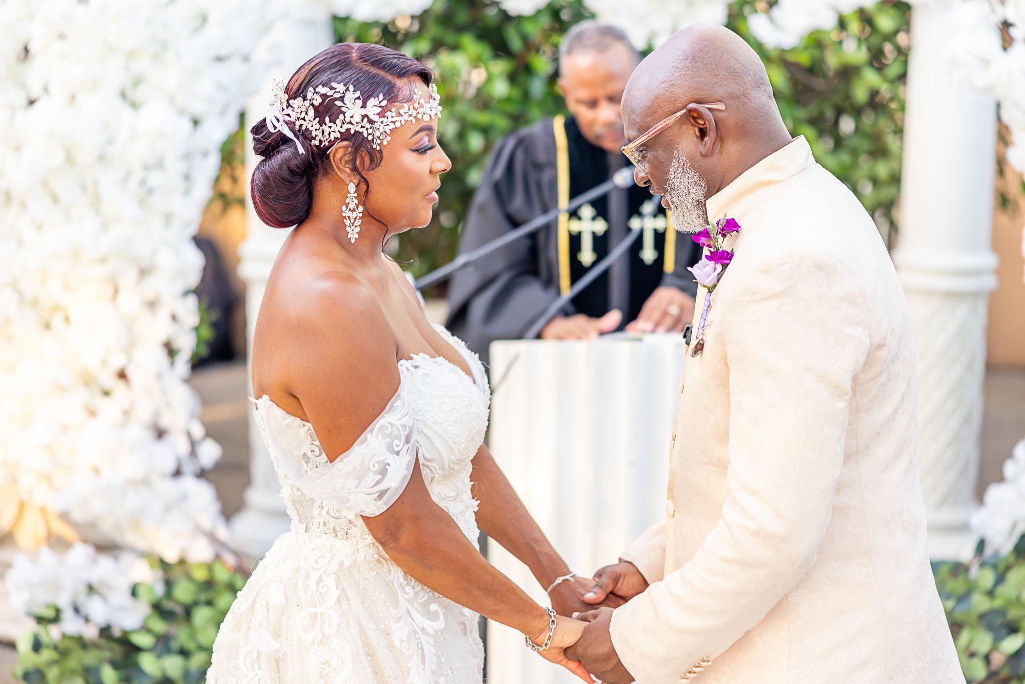 A couple celebrates during an outdoor garden wedding ceremony with guests seated in white chairs.