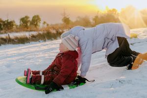 A series of sledding action shots at sunset shows someone gliding down a snowy hill on a bright green sled.