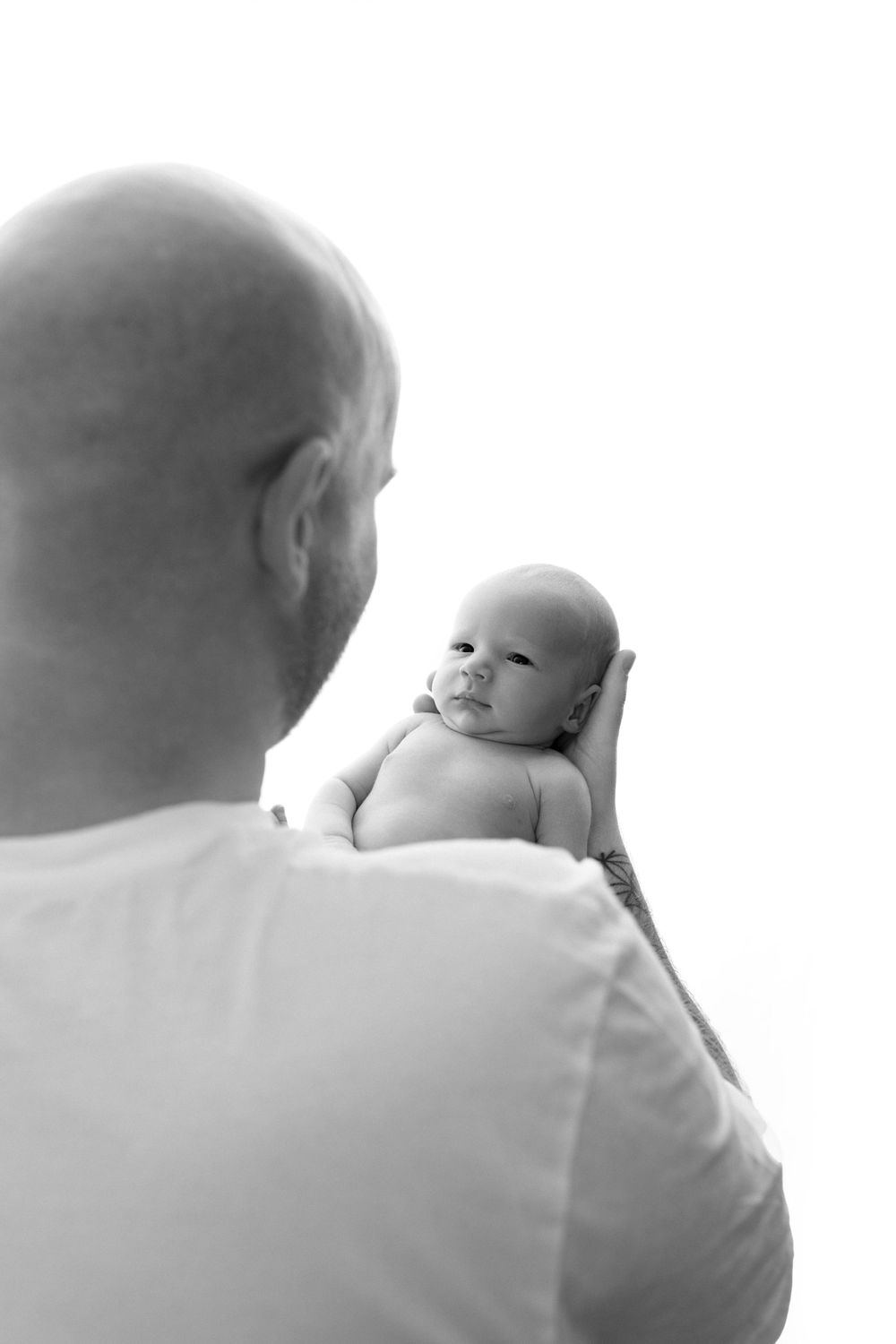 Black and white portrait of a newborn baby resting peacefully on someone's shoulder.