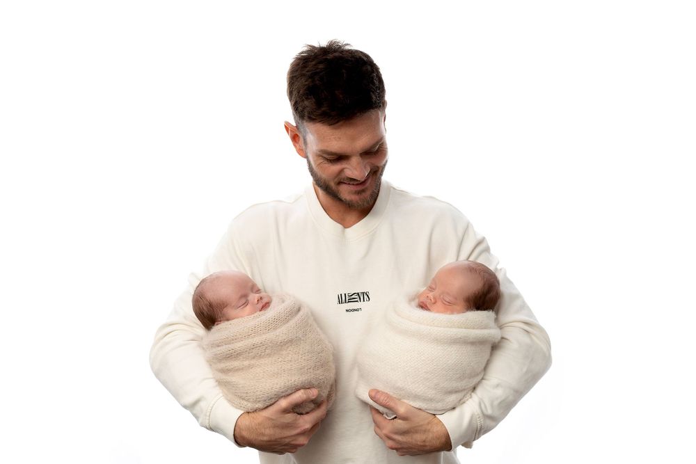 Person in white sweater holding two newborn babies in sequence of progressive poses showing different holding positions.