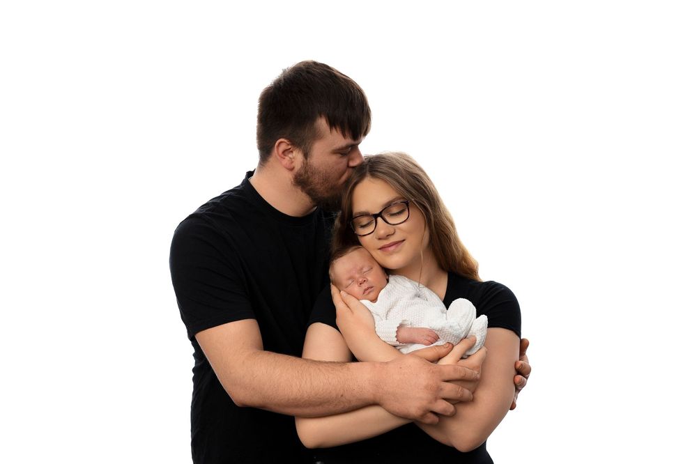 A couple in black shirts cuddles with their newborn baby in a series of intimate family portraits.