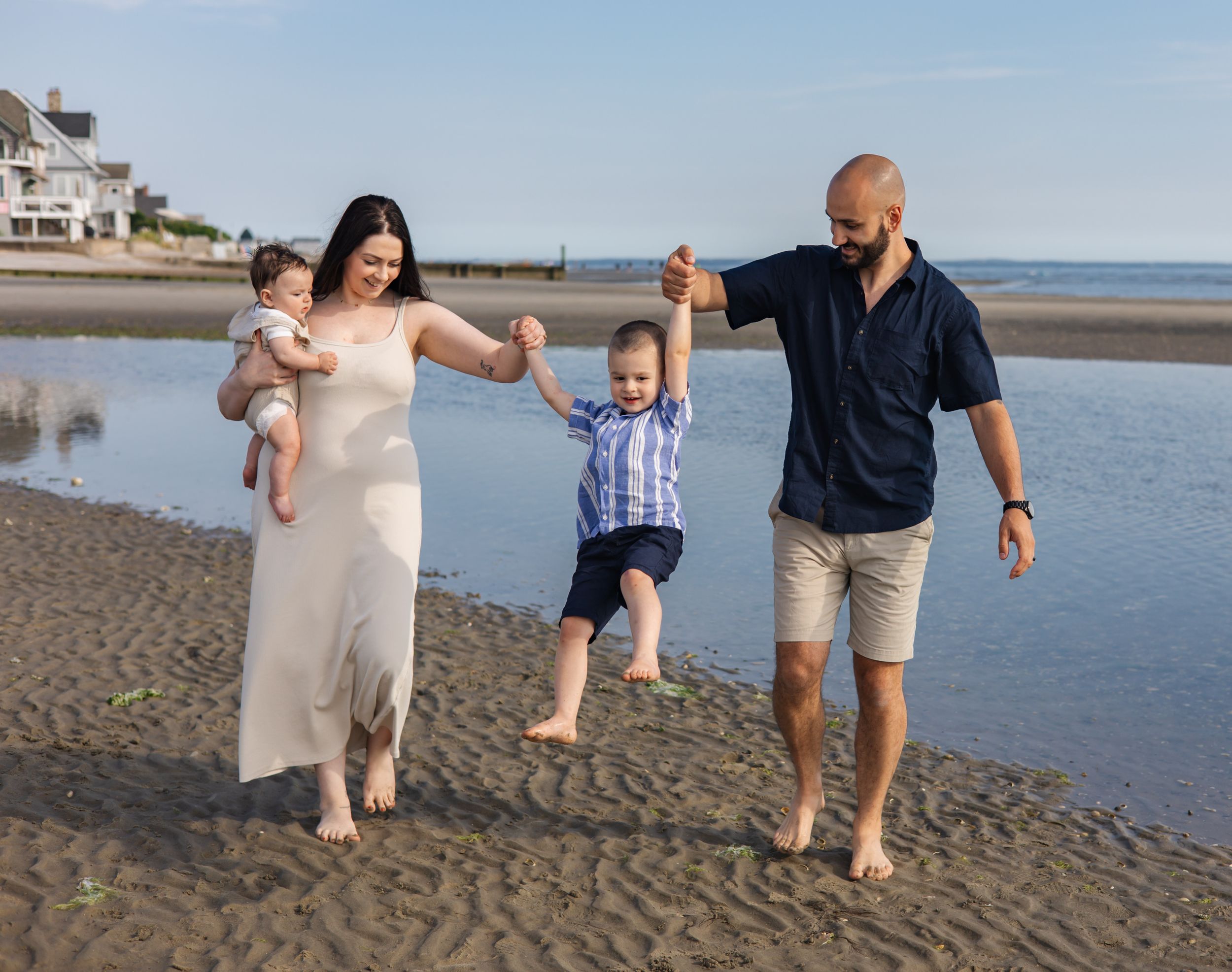 Family walking and playing together on beach at low tide.