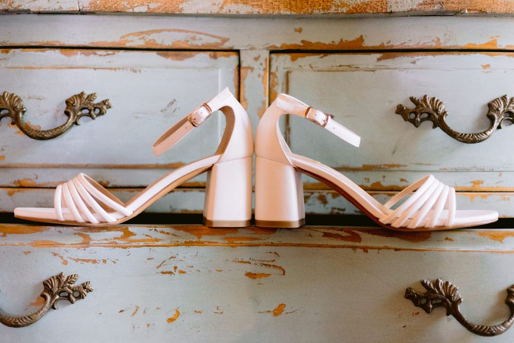Sapatos brancos da noiva junto a móvel antigo no Hotel Rural Casa dos Viscondes Várzea em Lamego