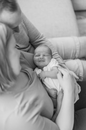 Black and white image of a sleeping newborn being gently cradled.