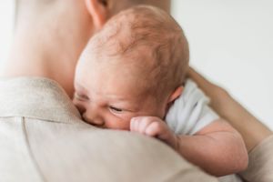 Close-up shot of a newborn resting on a parent's shoulder.