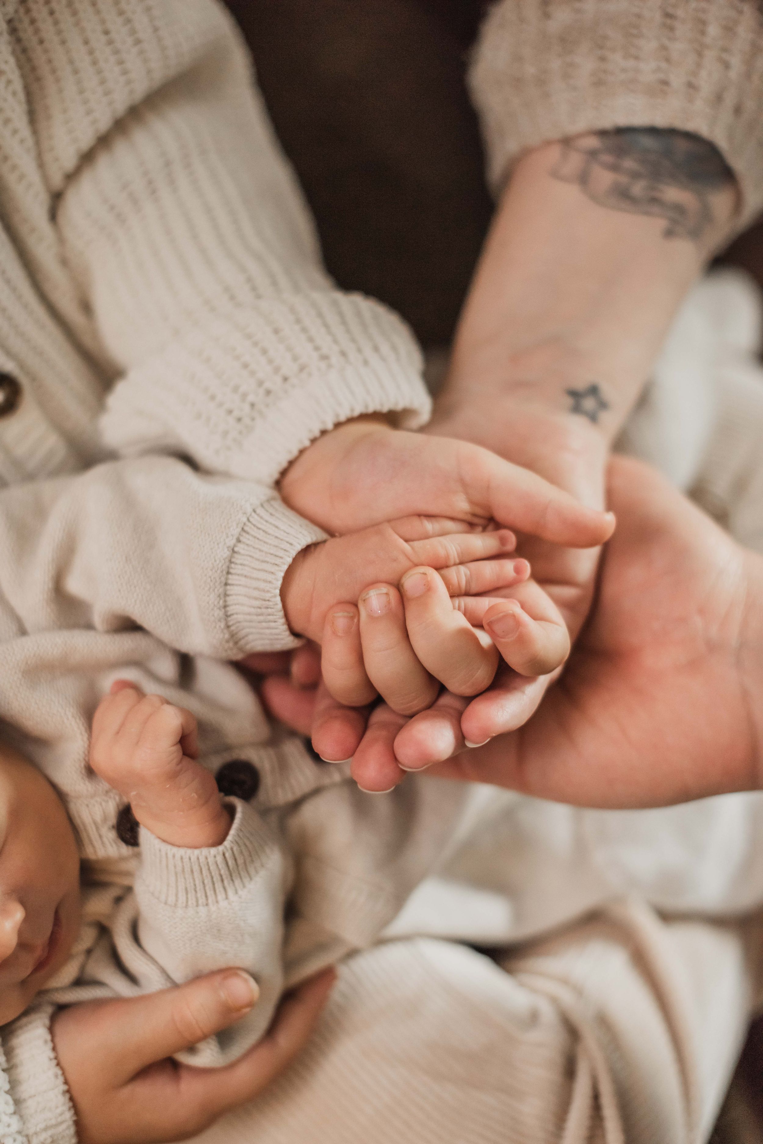 A series of tender close-up shots showing adult and baby hands gently touching in warm, neutral tones.