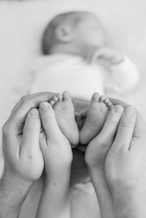 A series of four black and white close-up photographs showing tiny baby toes in a row.