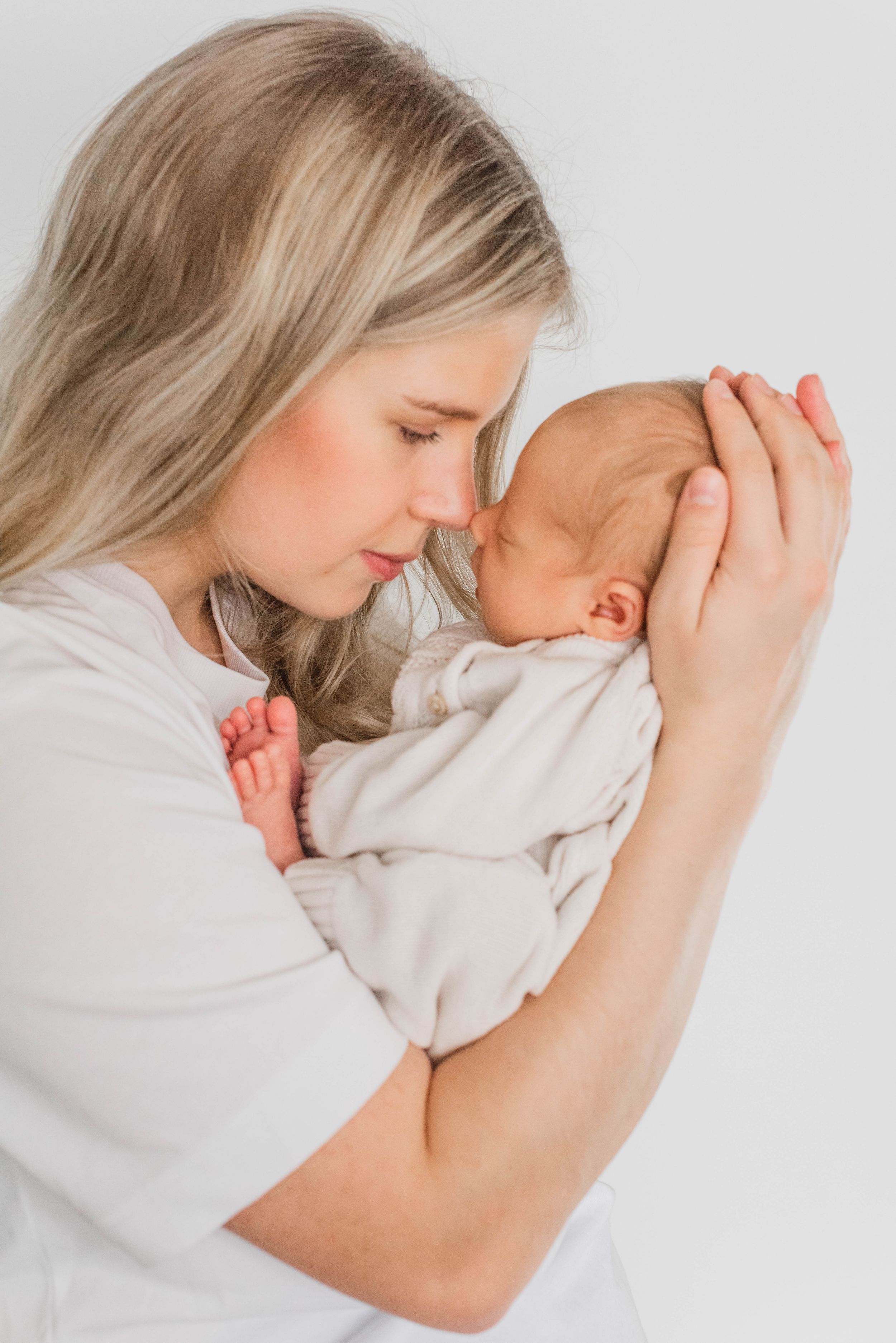 A tender moment between parent and newborn baby in white, shown in a series of intimate close-up photos.