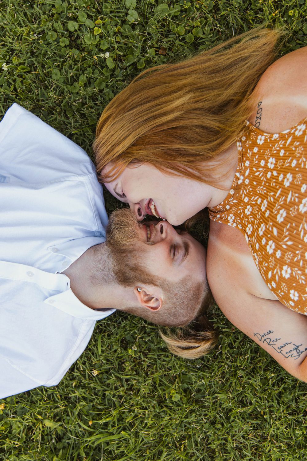 A couple laying on grass sharing a loving moment together.