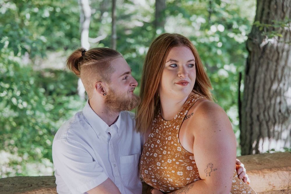 A romantic couple shares an intimate moment under trees in a park.