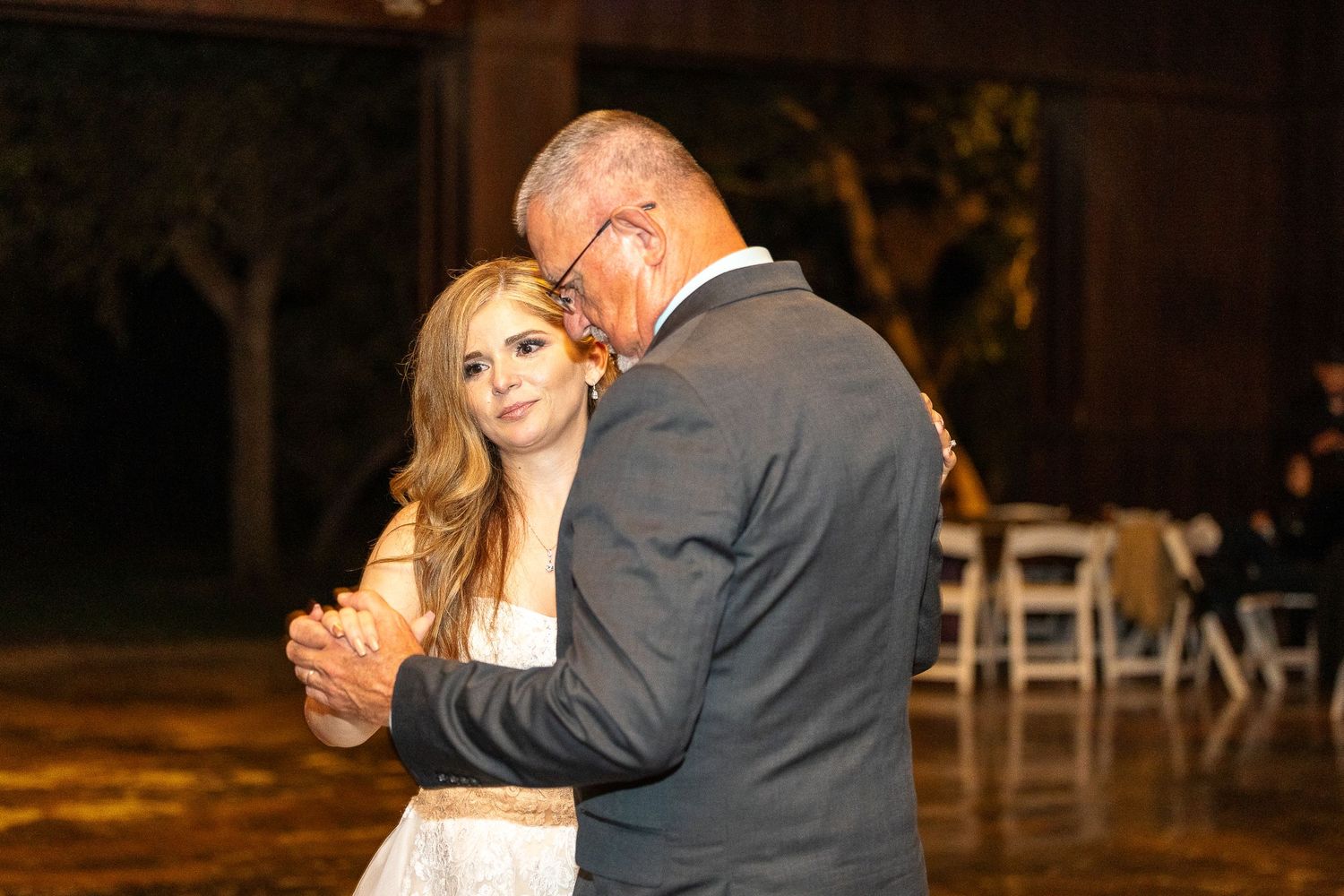 A couple shares their first dance at a rustic outdoor wedding reception.